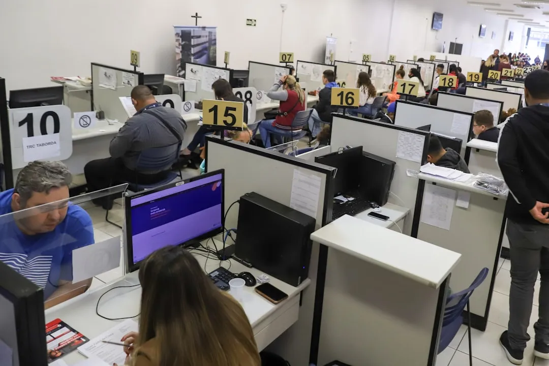 Pessoa digitando em notebook com tela desfocada de vagas, em escritório moderno, sem texto legível.