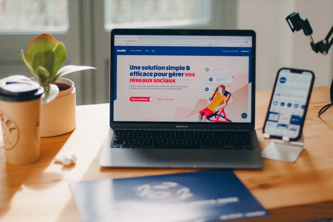 Laptop e celular próximos, representando pesquisa em sites de vagas locais