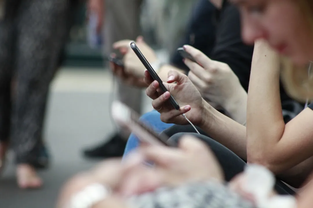Mãos preenchendo formulário de candidatura com celular mostrando página de vaga genérica.